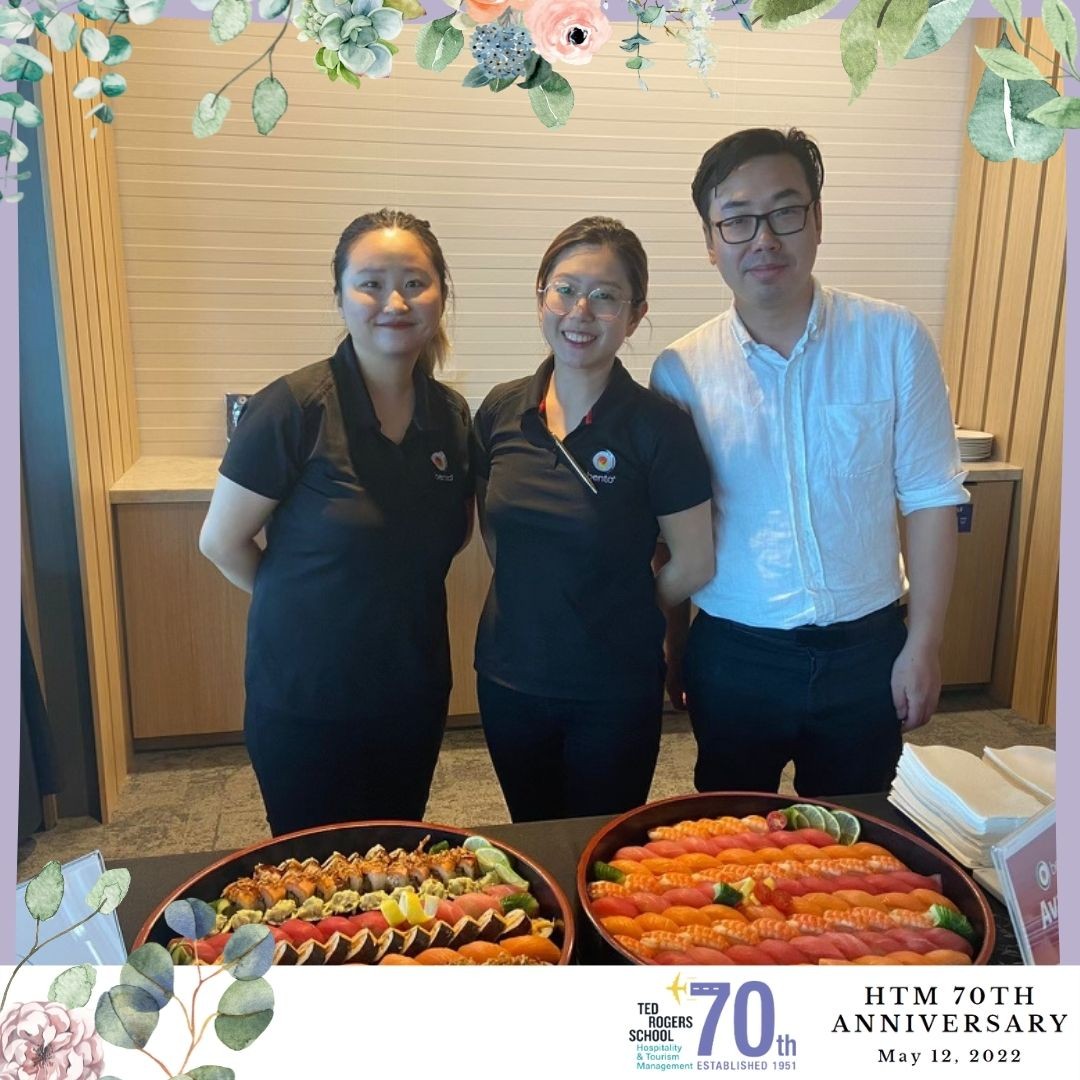 Three employees from a catering service at HTM's 70th anniversary event standing with their sushi spread displayed.